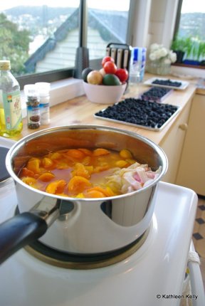 cumquat jam boiling. and blackberries ready for freezing in the background.